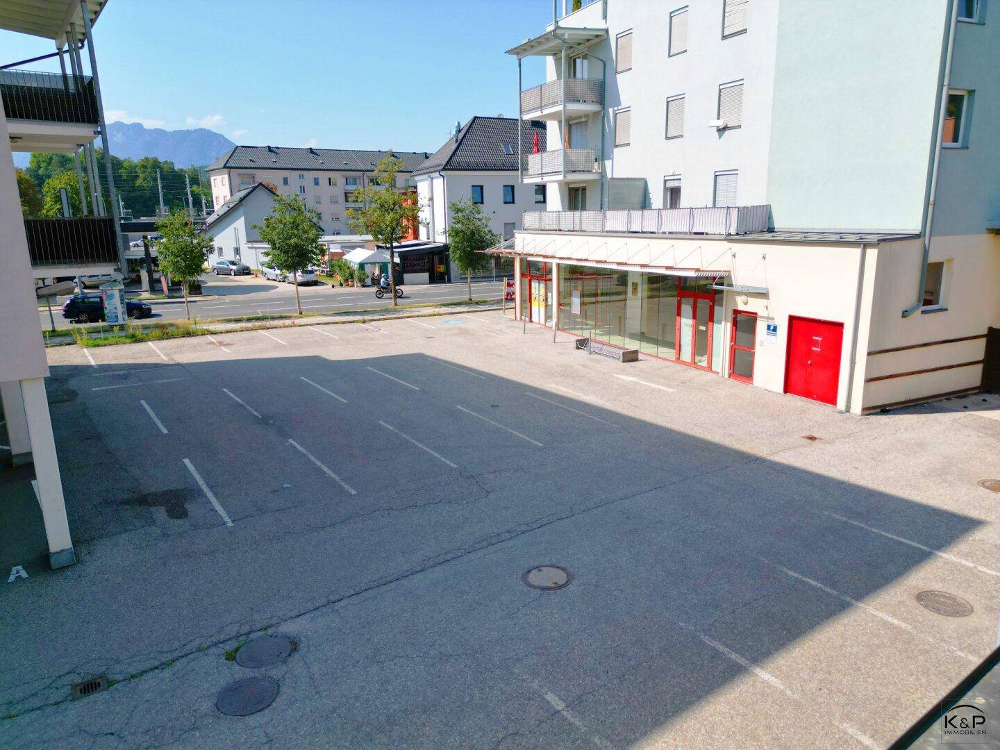 Ansicht des großen Außenparkplatzes vor den Ladenflächen im Erdgeschoss des modernen Gebäudes.