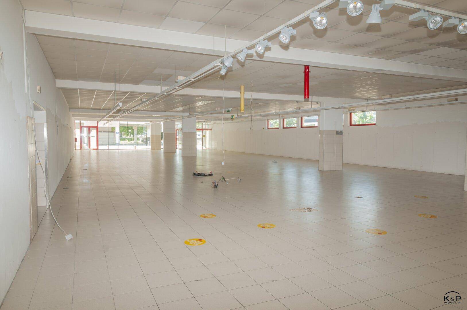 Geräumiger, leerstehender Gewerberaum mit Fliesenboden und Deckenbeleuchtung, bereit für den Ausbau.