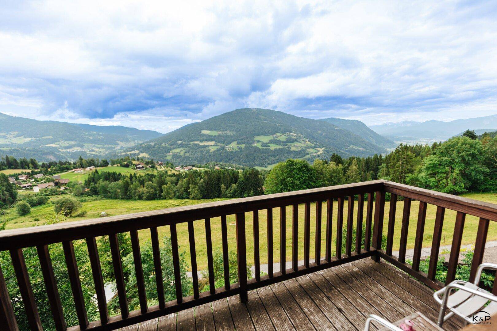 Großer Holzbalkon mit Panoramablick über grüne Hügel und Berge.