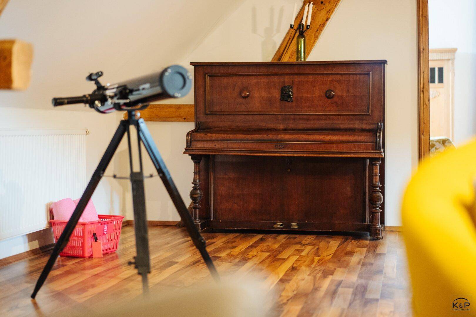 Detailansicht eines Flügels und Teleskops in einem Wohnbereich mit Holzboden.