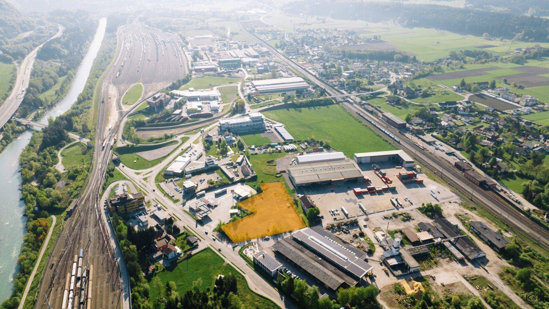 Weitläufige Luftaufnahme eines Grundstücks in einer gemischten Industrie- und Grünzone mit Fluss.