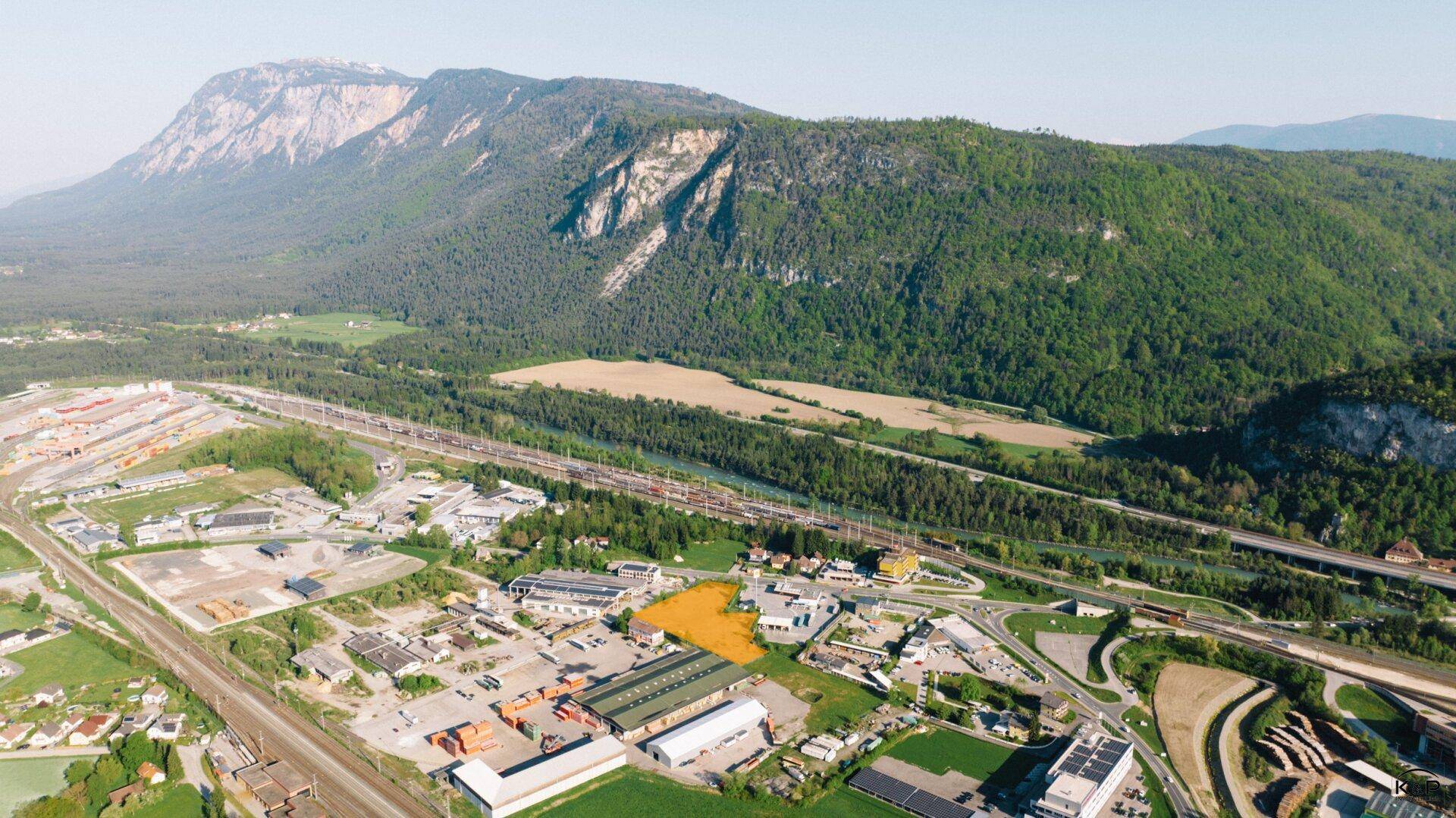 Panoramische Luftaufnahme eines Grundstücks in einer Industriezone mit weitem Blick auf Berge und Natur.