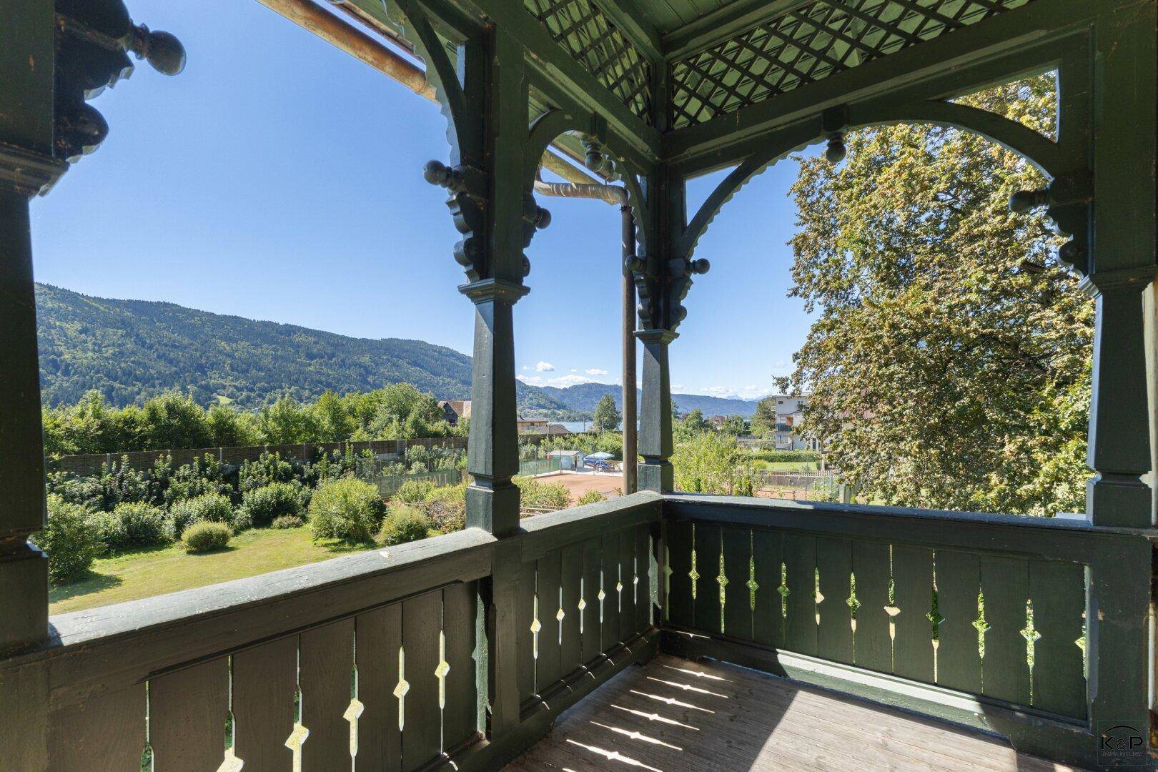 Historischer Holzbalkon mit kunstvollen Verzierungen und weitem Blick auf die umliegende Berglandschaft.