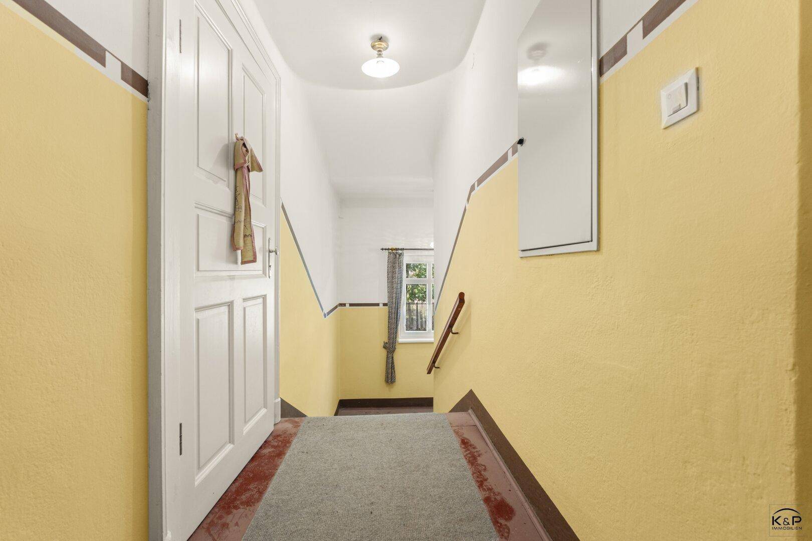 Treppenhaus mit gelb gestrichenen Wänden und Teppichboden, das die Etagen verbindet.