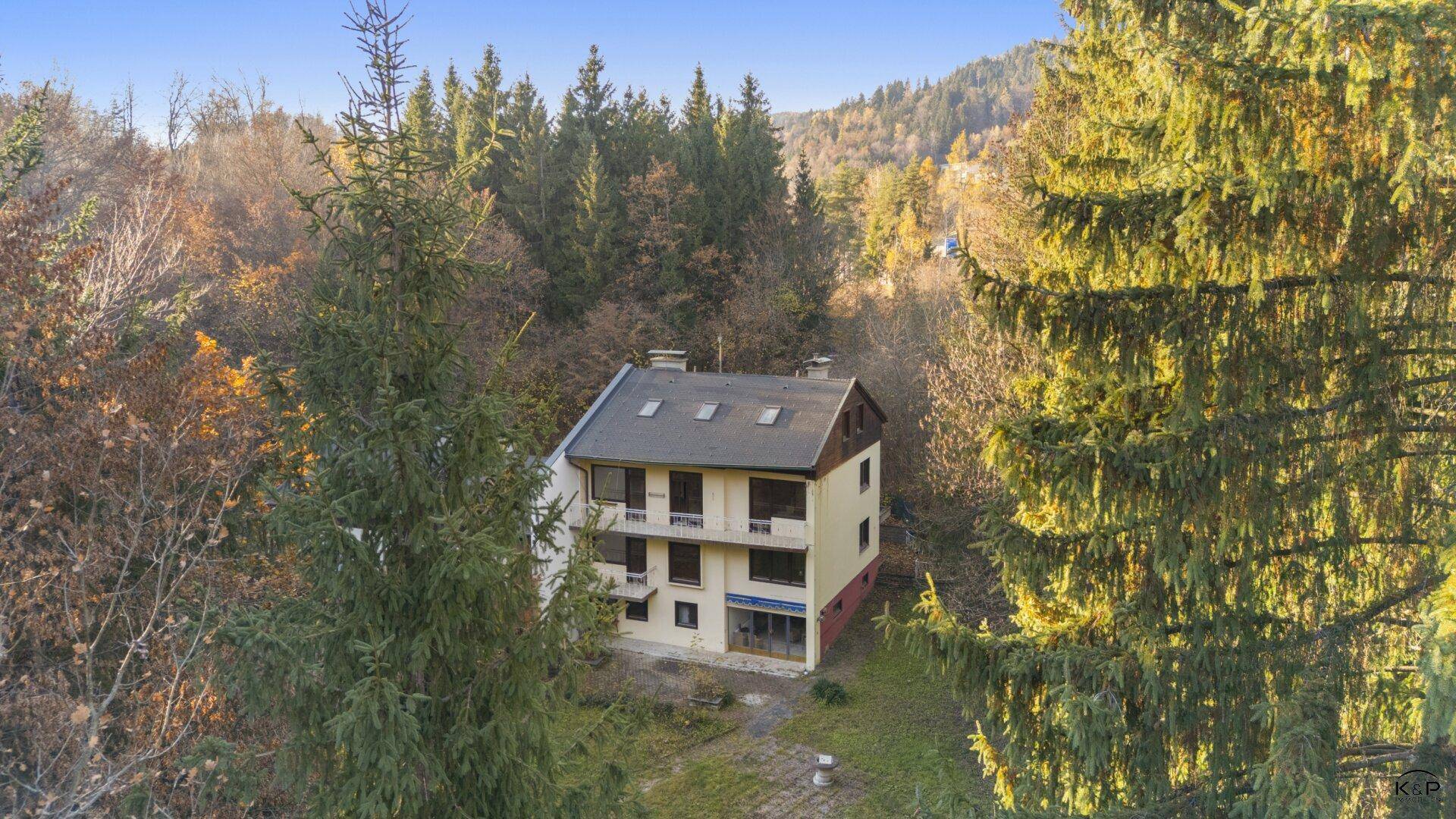 Luftaufnahme des Gebäudes, eingebettet in eine bewaldete Landschaft mit Herbstbäumen.