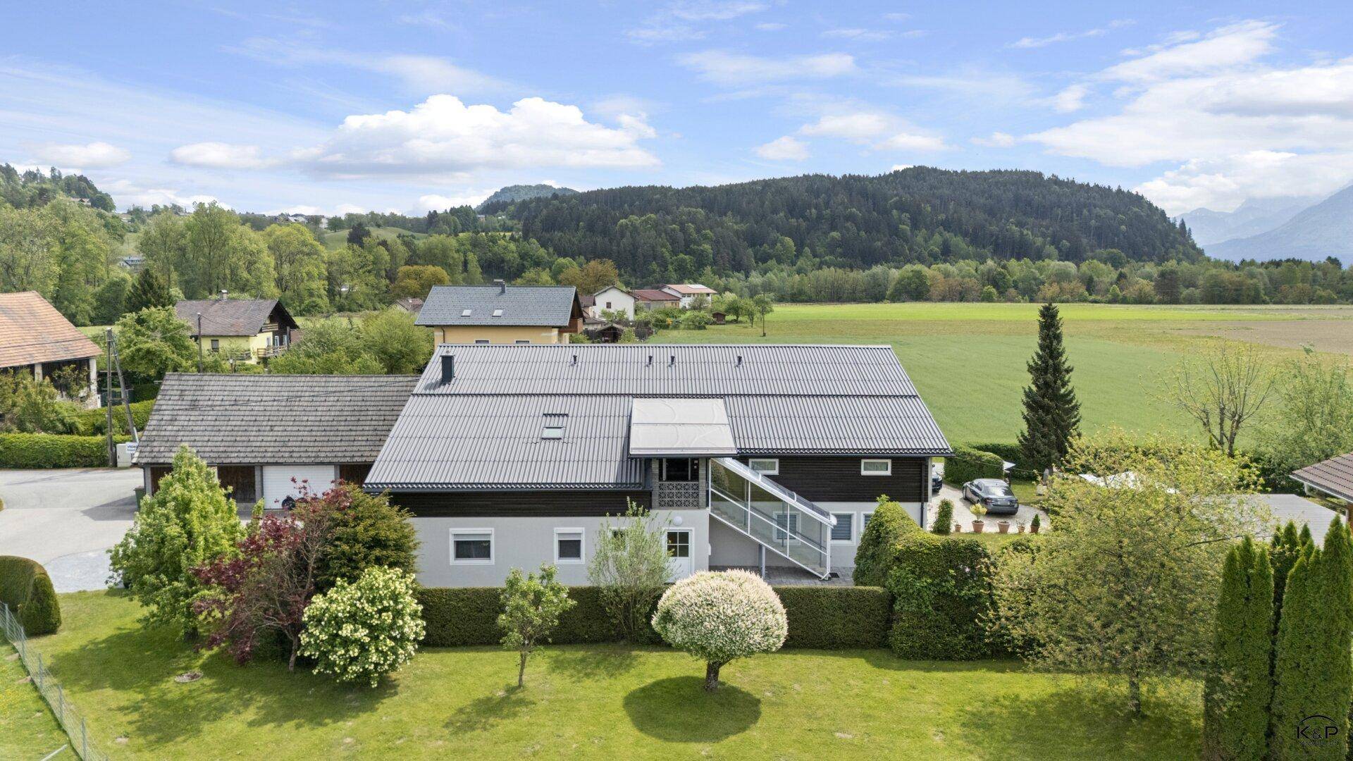 Ansicht des Hauses von oben mit Garten, umgeben von grünen Feldern und bewaldeten Hügeln.