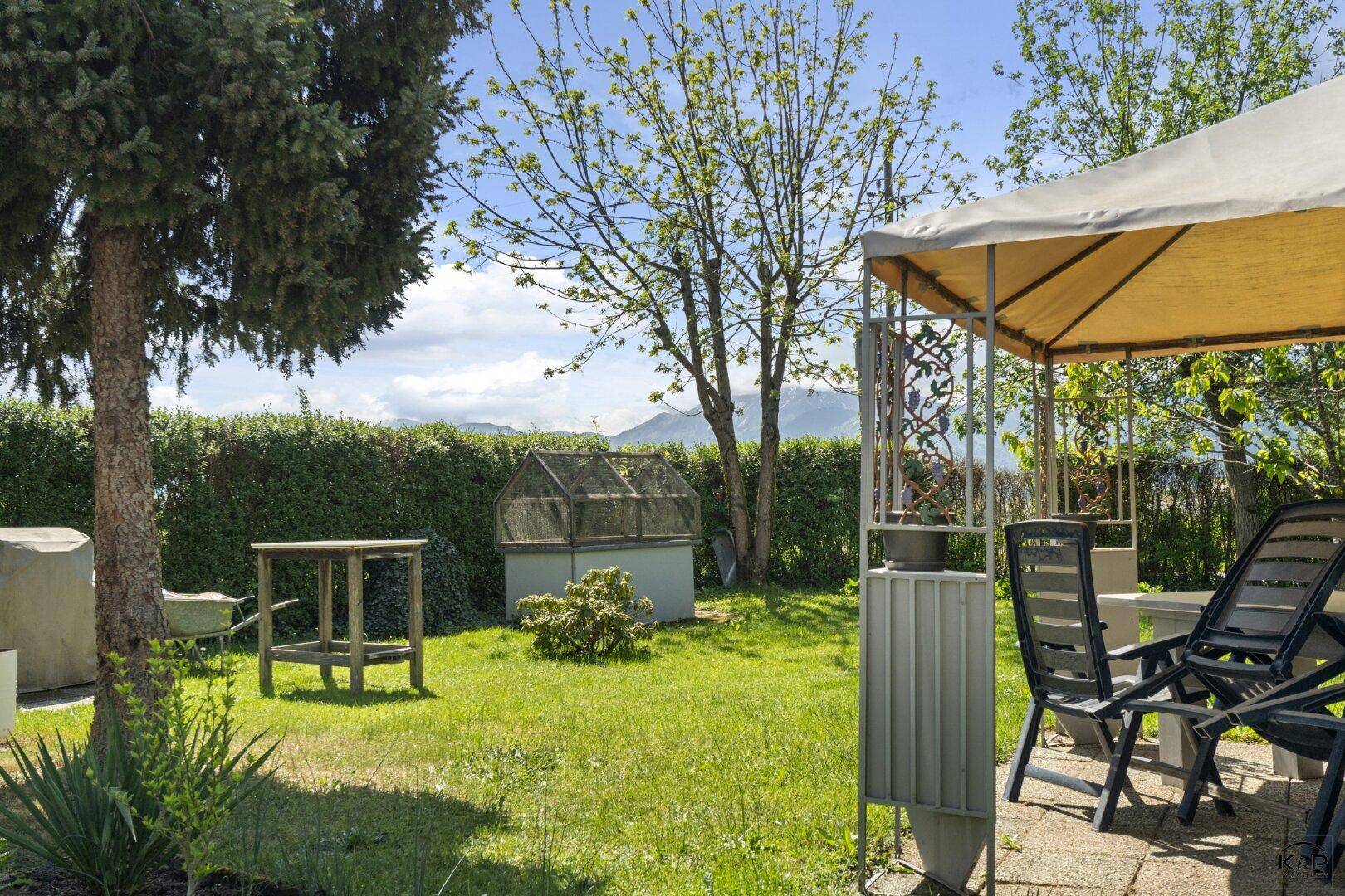 Gemütlicher Gartenbereich mit Sitzgelegenheiten unter einem Pavillon und Bergblick im Hintergrund.