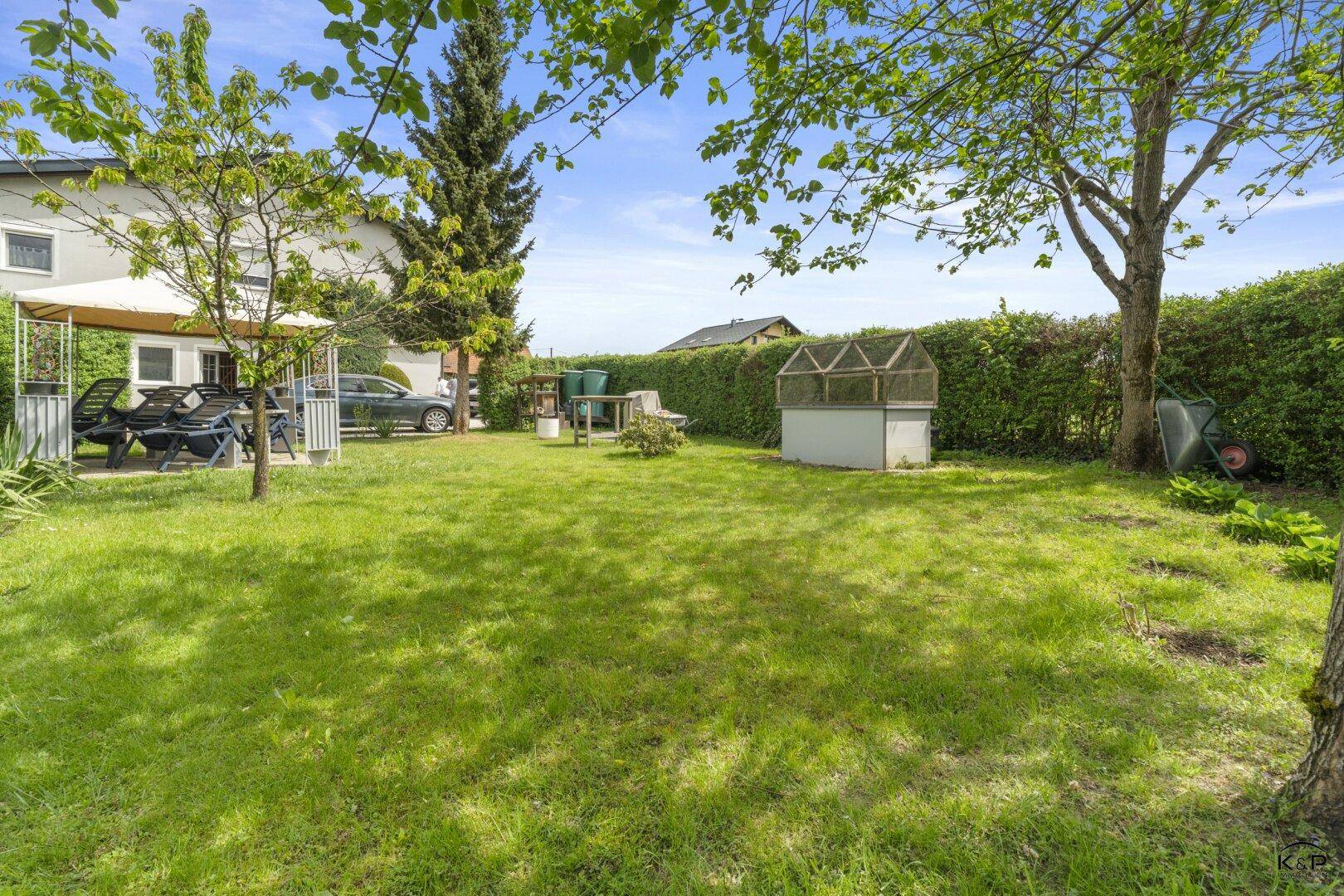 Weitläufiger Garten mit Rasenfläche, Pavillon und Blick auf das Haus und die umliegende Natur.