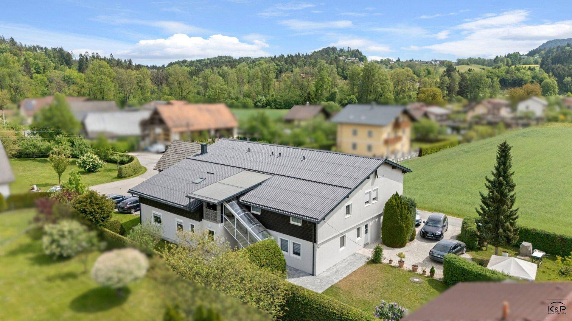 Vogelperspektive des Hauses mit Vorgarten, Einfahrt und geparkten Autos in ländlicher Umgebung.
