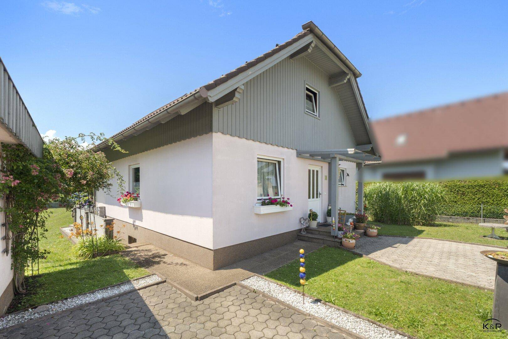 Vorderansicht eines Einfamilienhauses mit gepflegtem Vorgarten und gepflasterter Auffahrt.