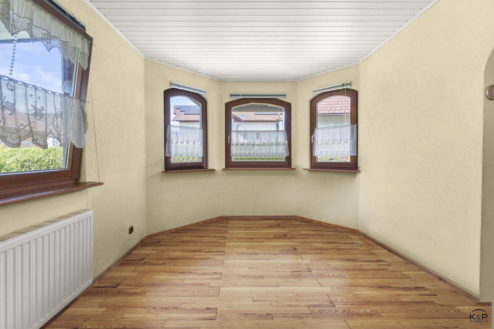 Gemütlicher Erkerbereich mit Holzparkett, mehreren Fenstern und einem Heizkörper.