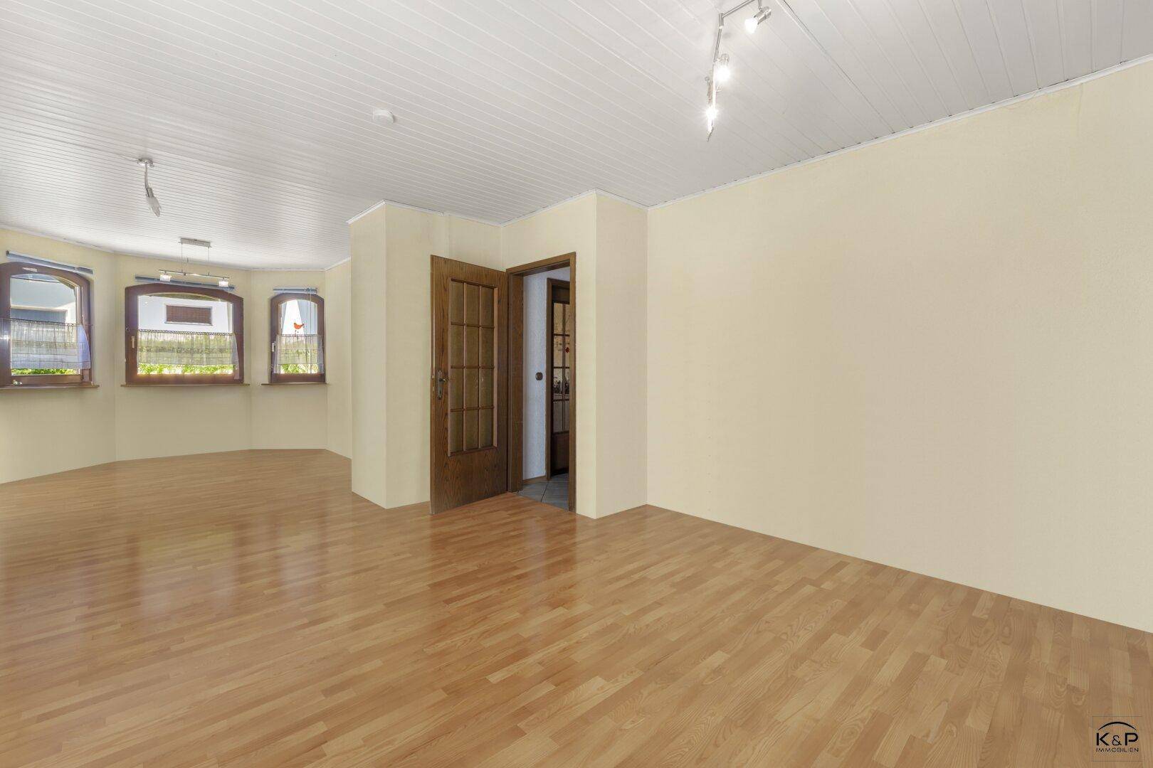 Geräumiger, heller Wohnbereich mit Holzparkettboden und einem charmanten Erkerfenster.