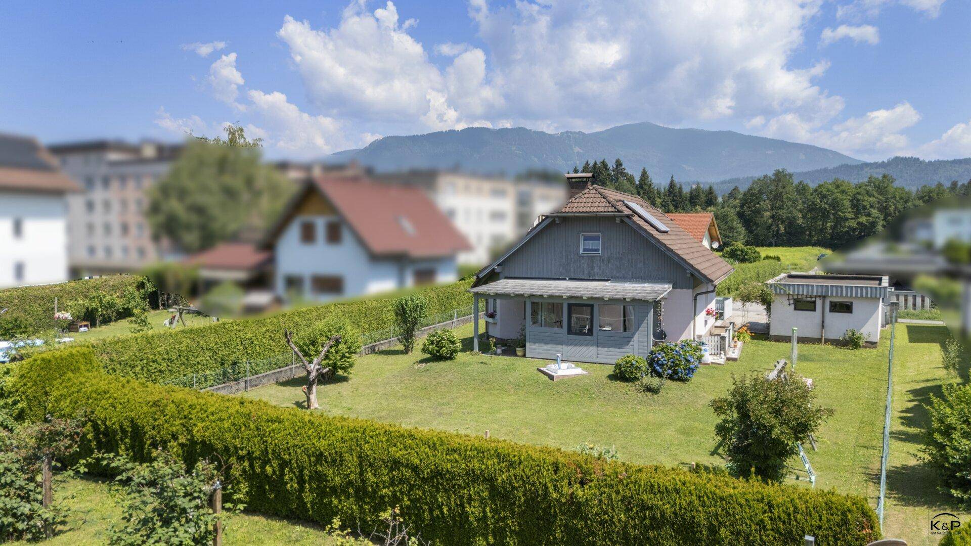 Vogelperspektive auf ein Einfamilienhaus mit großem, gepflegtem Garten und Heckenbegrenzung.