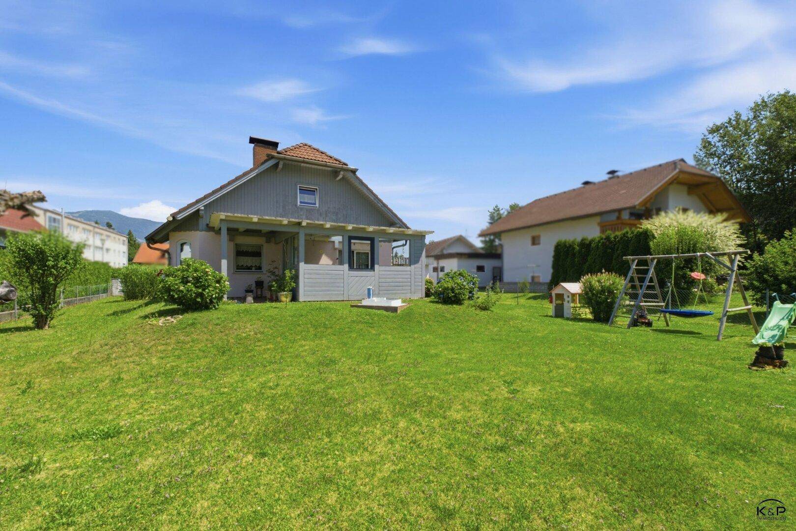 Großer Garten mit Rasenfläche, Schaukel und Spielhaus, ideal für Familien.