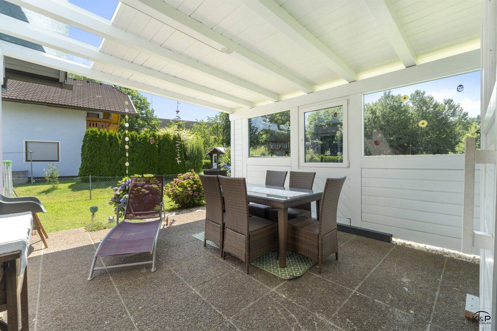 Überdachte Terrasse mit Esstisch und Stühlen, ideal für Mahlzeiten im Freien.