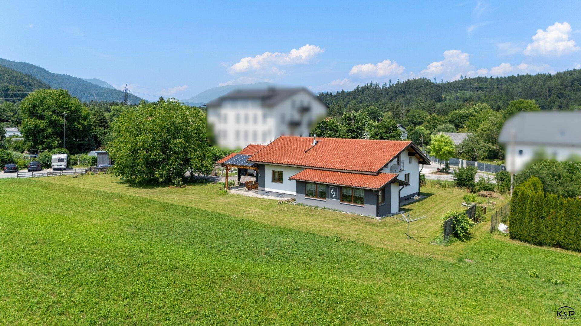 Weitläufiges Grundstück mit Einfamilienhaus, großer Rasenfläche und umgebender Natur.