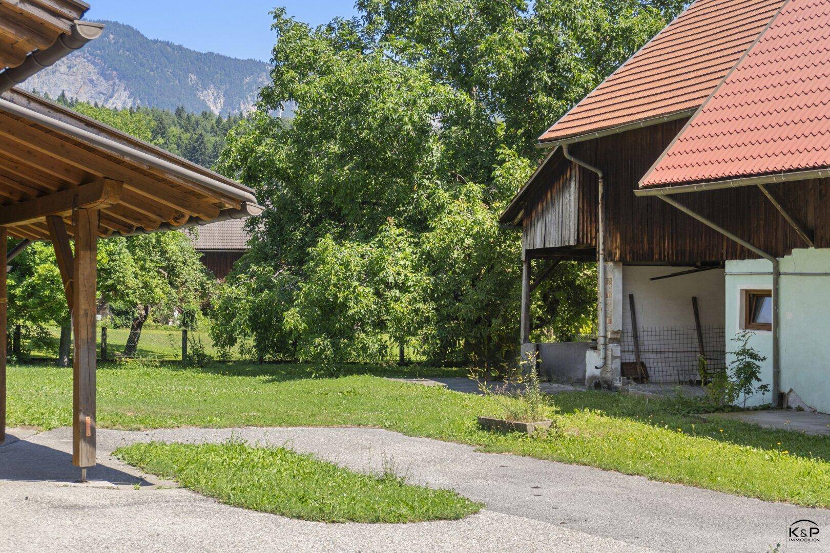 Überdachter Stellplatz und Zufahrt zum Haus mit angrenzendem Gartenbereich.