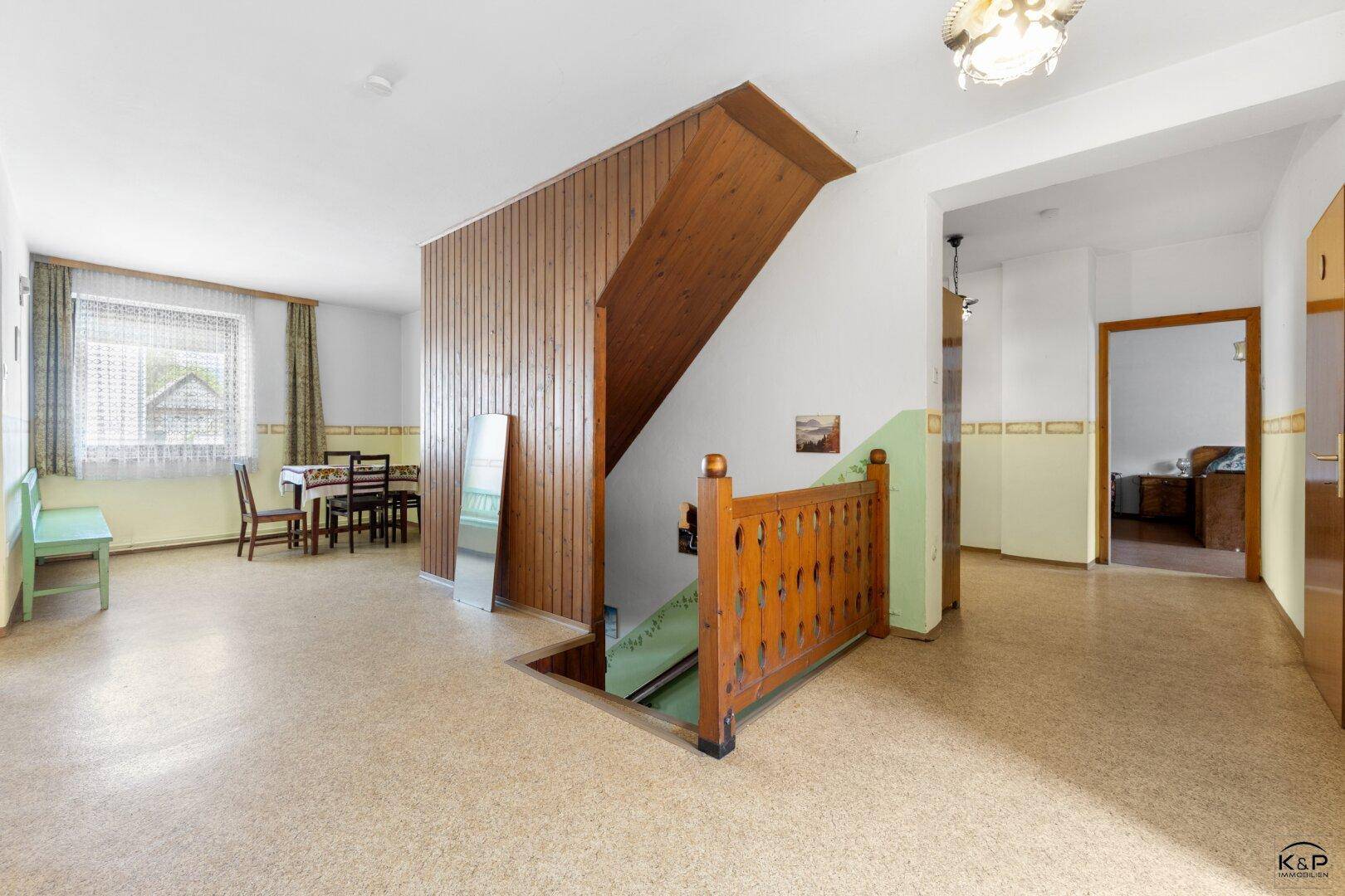 Heller Flur mit Holztreppe, Essbereich und Blick in angrenzende Zimmer.