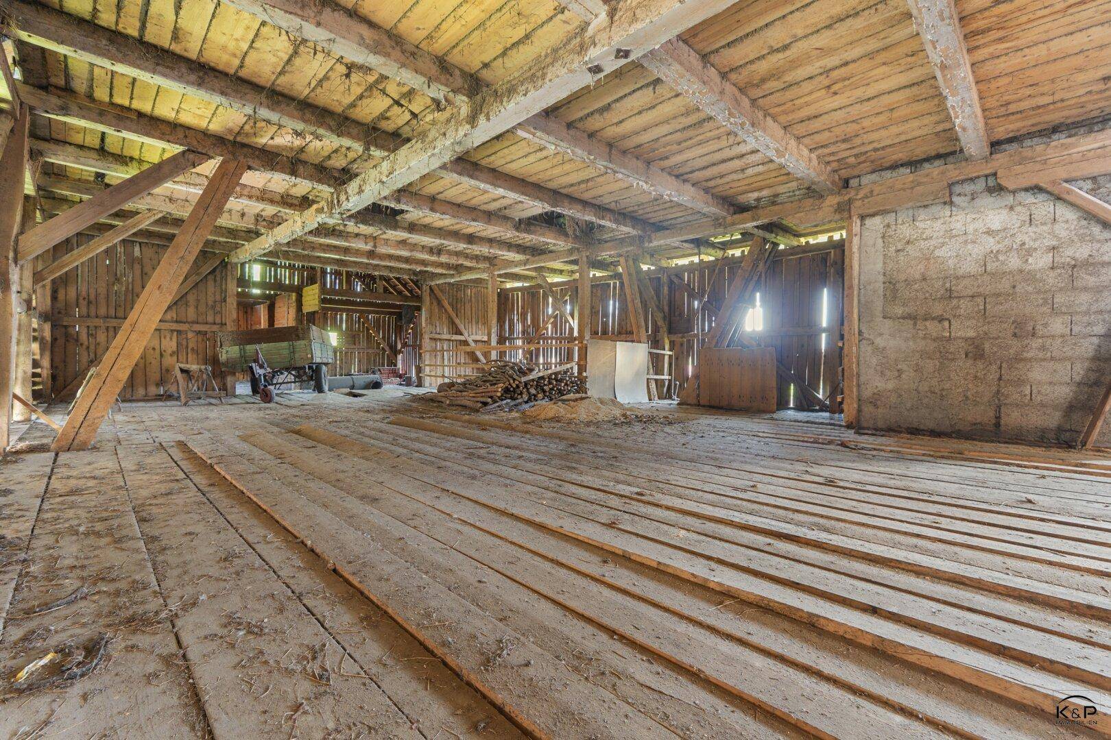 Geräumiger Scheunenbereich mit Holzbalken und Dielenboden, bietet viel Ausbaupotenzial.