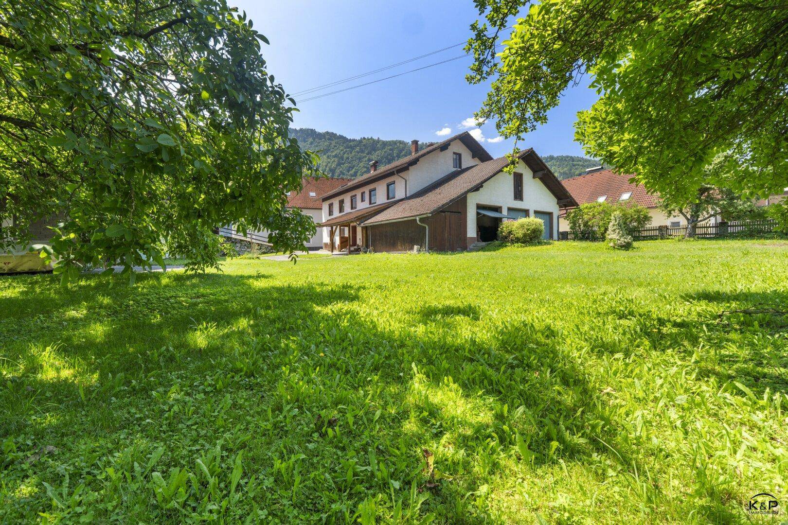 Geräumiger Gartenbereich vor dem Haus mit viel Grün und einem weiten Blick auf die Berge.