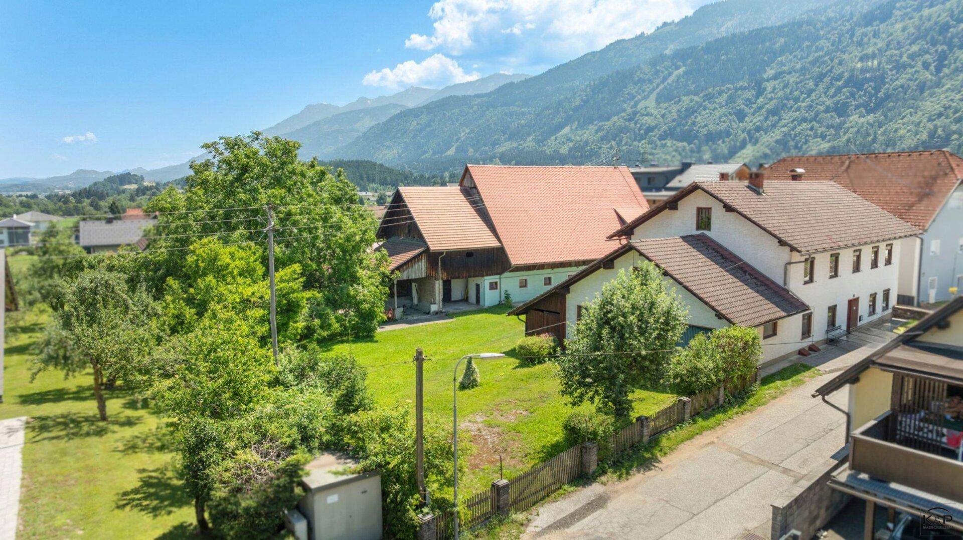 Weitläufiger Gartenbereich mit altem Baumbestand und Blick auf die umliegenden Berge.