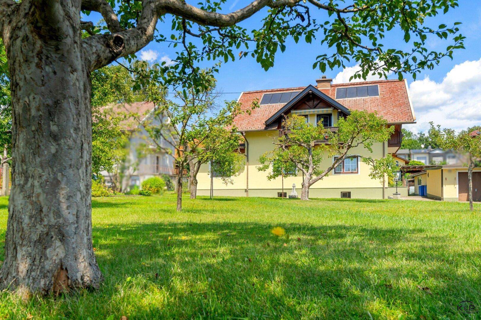 Großzügiger, gepflegter Garten mit altem Baumbestand und Blick auf das sonnige Einfamilienhaus.