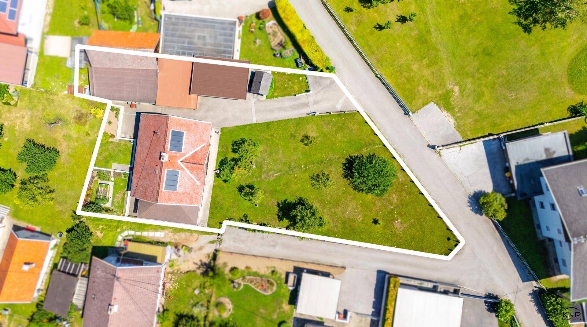 Luftaufnahme des Grundstücks mit weiß eingezeichneten Grenzen, zeigt das Haus und die Nebengebäude.