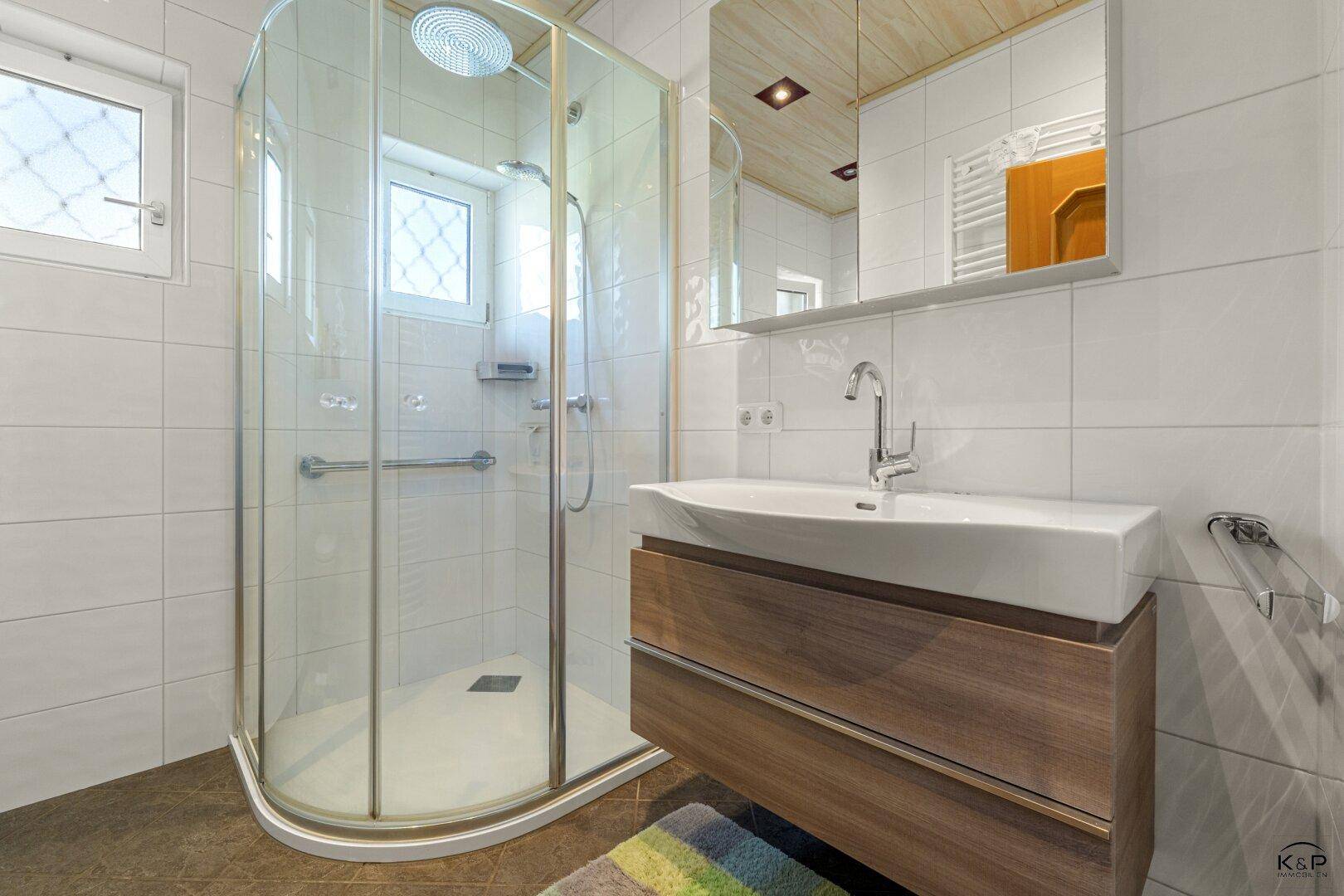 Modernes Badezimmer mit Eckdusche, stilvollem Waschtisch und Fenster für natürliches Licht.