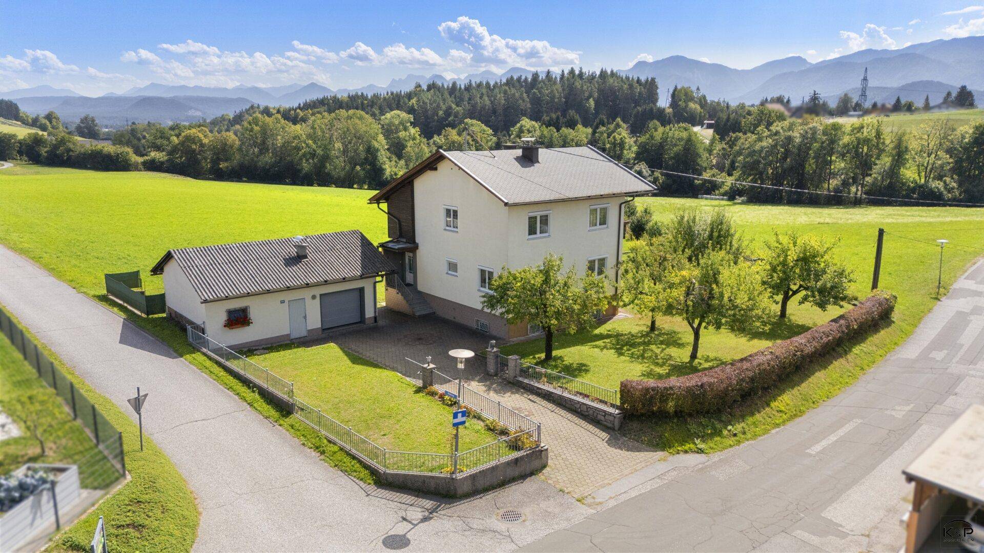 Ansicht des Hauses mit angrenzender Garage und gepflegtem Vorgarten in ländlicher Umgebung.