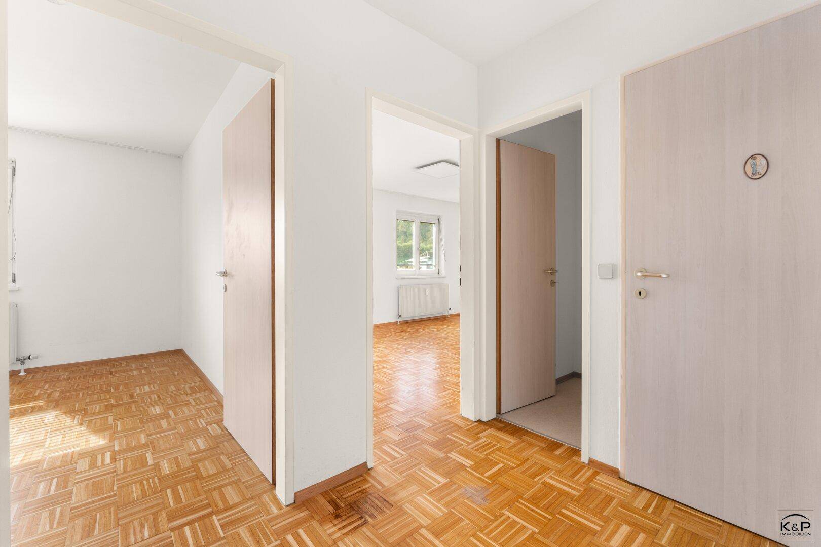 Heller Flur mit Parkettboden und mehreren Türen, die zu den angrenzenden Zimmern führen.