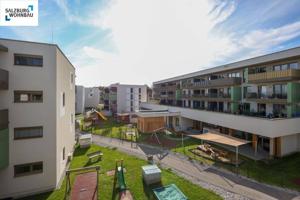 Gesamtansicht der modernen Wohnanlage mit mehreren Gebäuden und einem zentralen Kinderspielplatz.