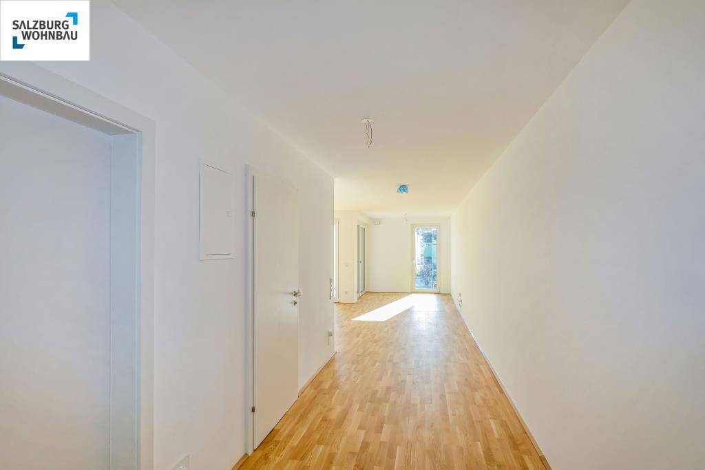 Heller Flur mit Holzboden, der zu den verschiedenen Räumen der Wohnung führt.