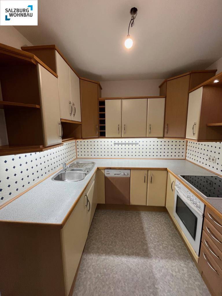Voll ausgestattete Küche mit Einbauschränken, Spüle und Kochfeld, in gutem Zustand.