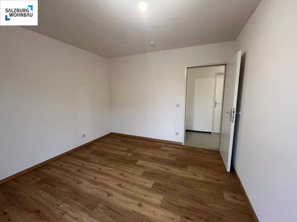 Leeres Schlafzimmer mit Laminatboden und weiß gestrichenen Wänden, bereit zum Einzug.