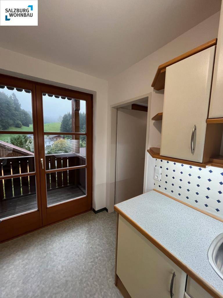 Küchenzeile mit Spüle, Arbeitsplatte und Zugang zu einem Balkon mit Aussicht auf die Landschaft.