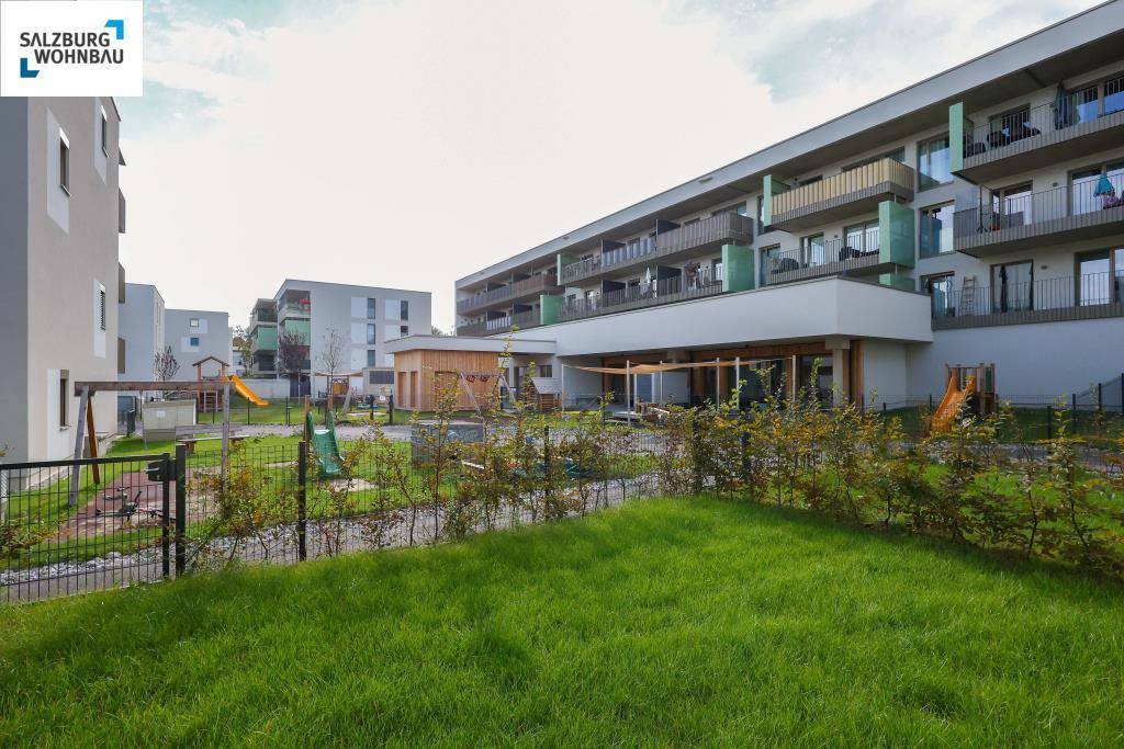 Moderne Wohnanlage mit gepflegten Grünflächen und einem gemeinschaftlichen Spielplatz für Kinder.
