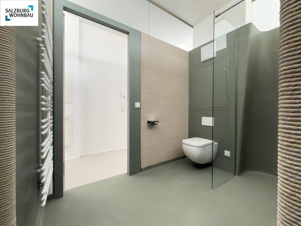 Modernes WC mit Wand-WC, beheiztem Handtuchhalter und minimalistischem Design.