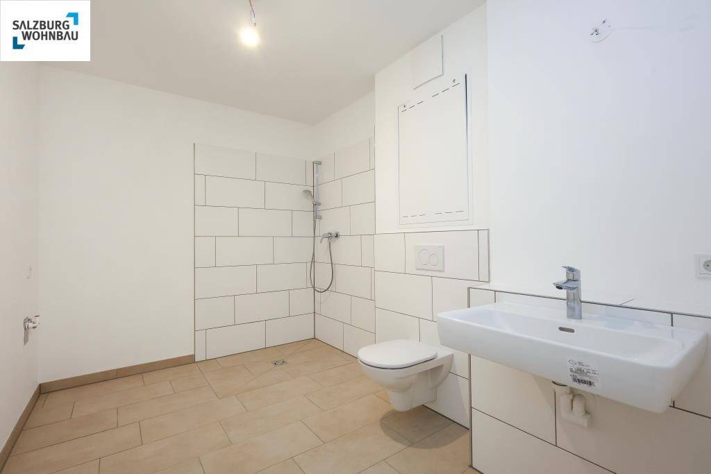 Modernes Badezimmer mit Dusche, wandhängendem WC und Waschbecken in Weiß.
