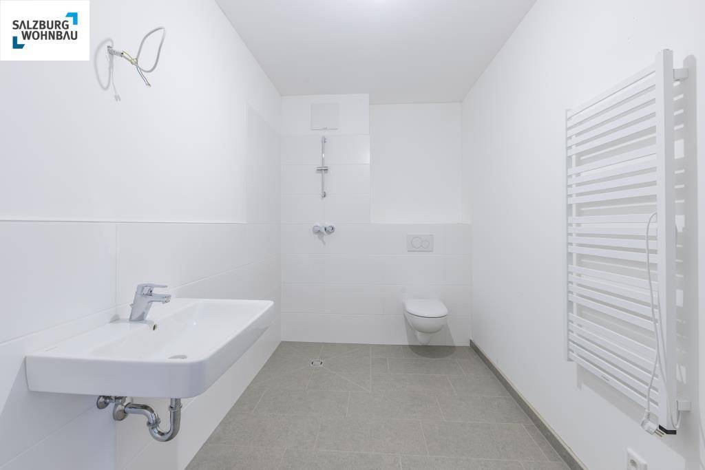 Modernes Badezimmer mit Dusche, WC, Waschbecken und beheiztem Handtuchhalter.