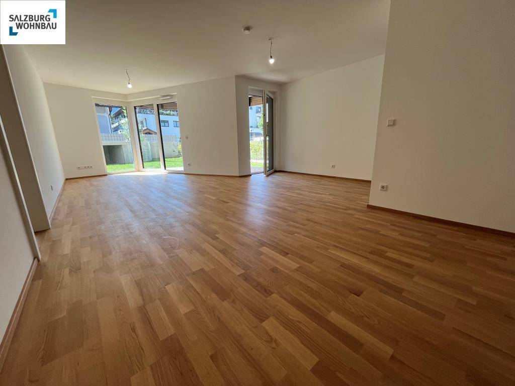 Geräumiger, heller Wohnbereich mit Parkettboden und großen Glasfronten zum Garten.