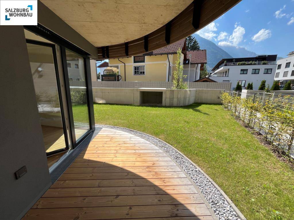 Geschwungene Holzterrasse mit Rasenfläche und beeindruckendem Bergblick im Hintergrund.