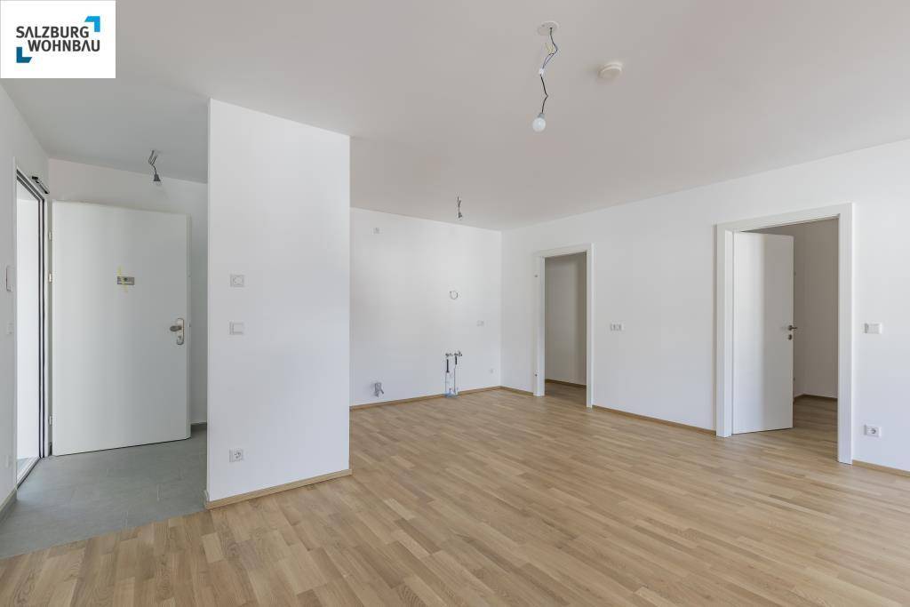 Leerer, heller Raum mit weiß gestrichenen Wänden und neuem Parkettboden, bereit für die Einrichtung.