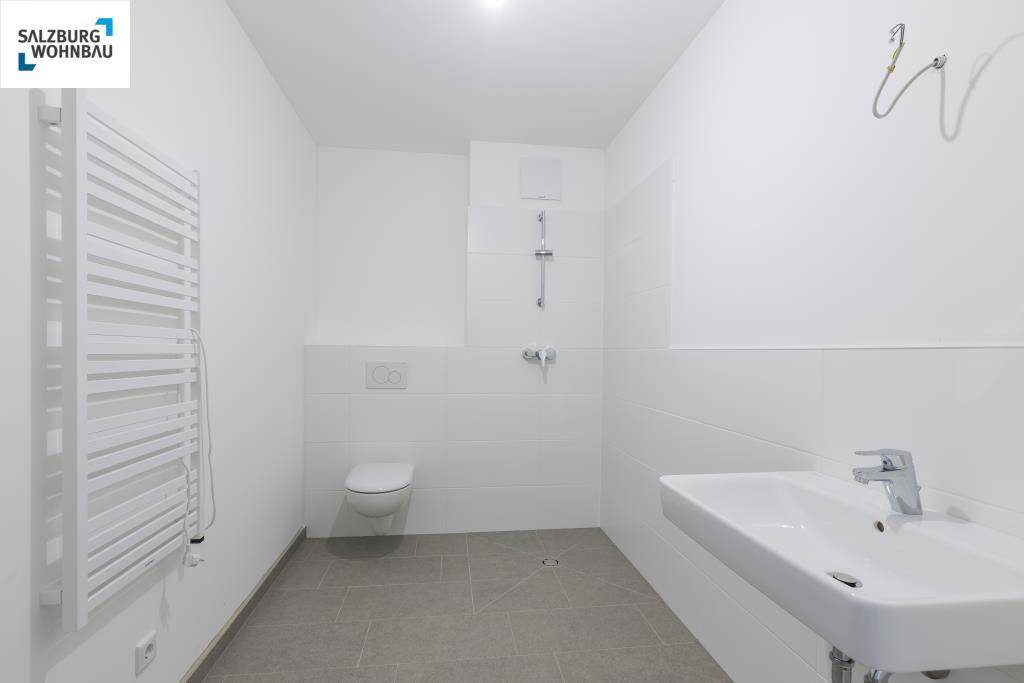 Modernes Badezimmer in Weiß mit Dusche, WC, Einzelwaschbecken und Handtuchheizkörper.