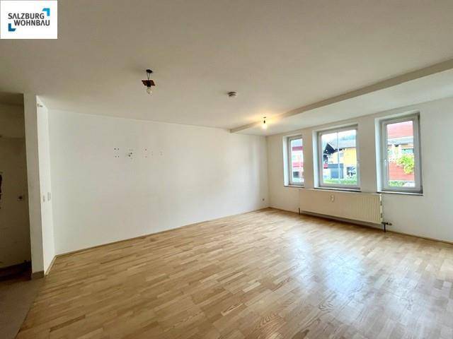 Heller Wohnraum mit Parkettboden und mehreren Fenstern, die viel Tageslicht hereinlassen und eine angenehme Atmosphäre schaffen.