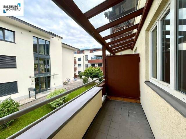 Überdachter Balkon mit Fliesenboden und seitlichem Blick auf die Nachbarschaft, bietet Schutz und Privatsphäre.