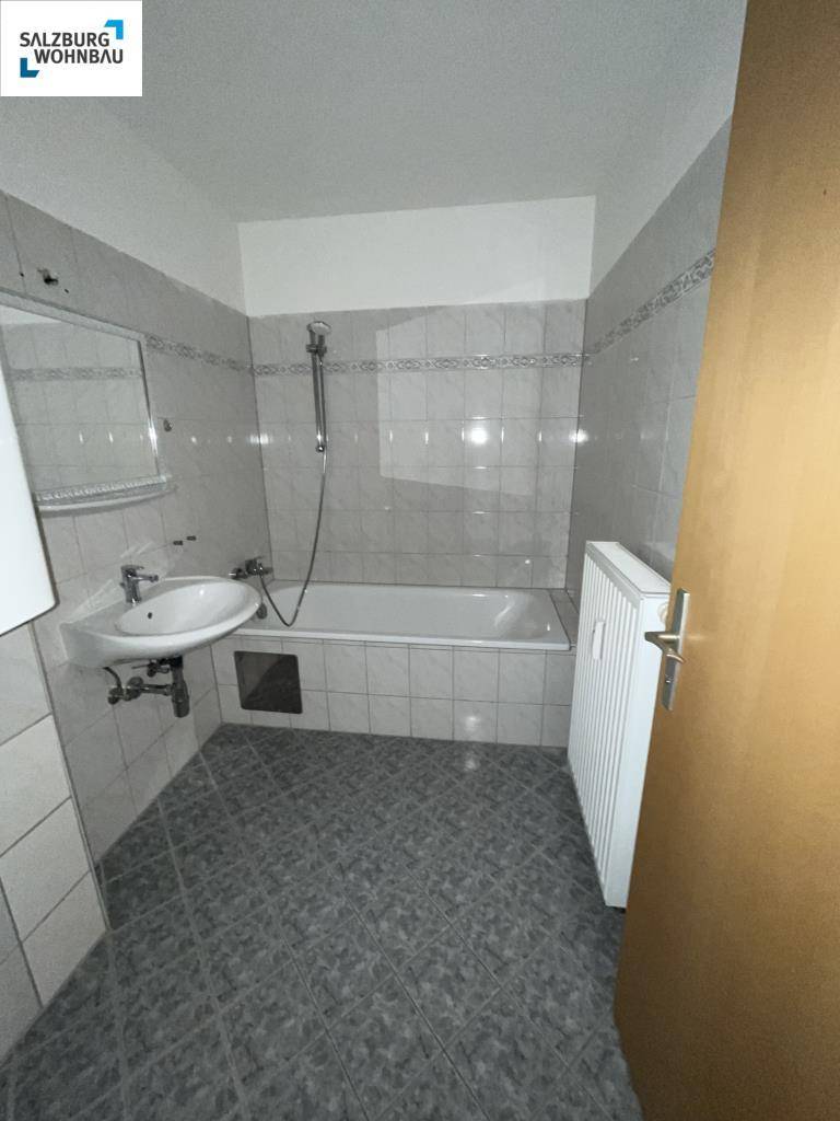Funktionales Badezimmer mit Badewanne, Waschbecken und hellen Fliesen.