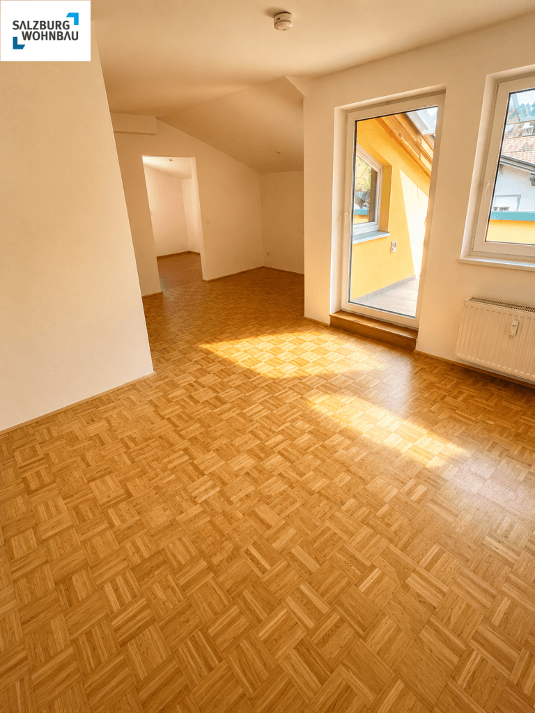 Heller Wohnraum mit Parkettboden und Zugang zu einem sonnigen Balkon.