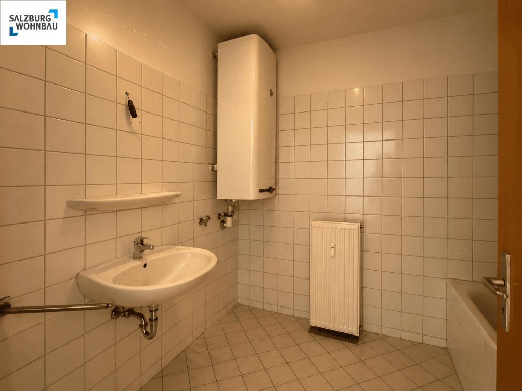 Funktionales Badezimmer mit weißen Fliesen, Waschbecken, Warmwasserboiler und Badewanne.