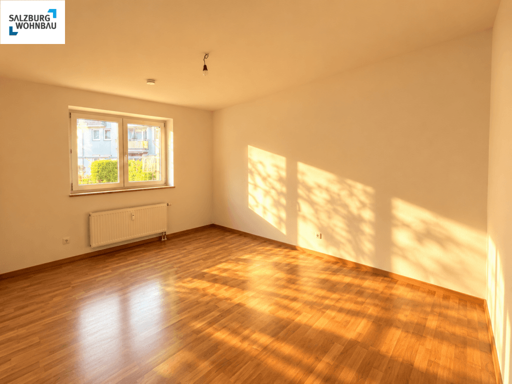 Lichtdurchflutetes Zimmer mit Parkettboden und einem Fenster, das viel Tageslicht hereinlässt.