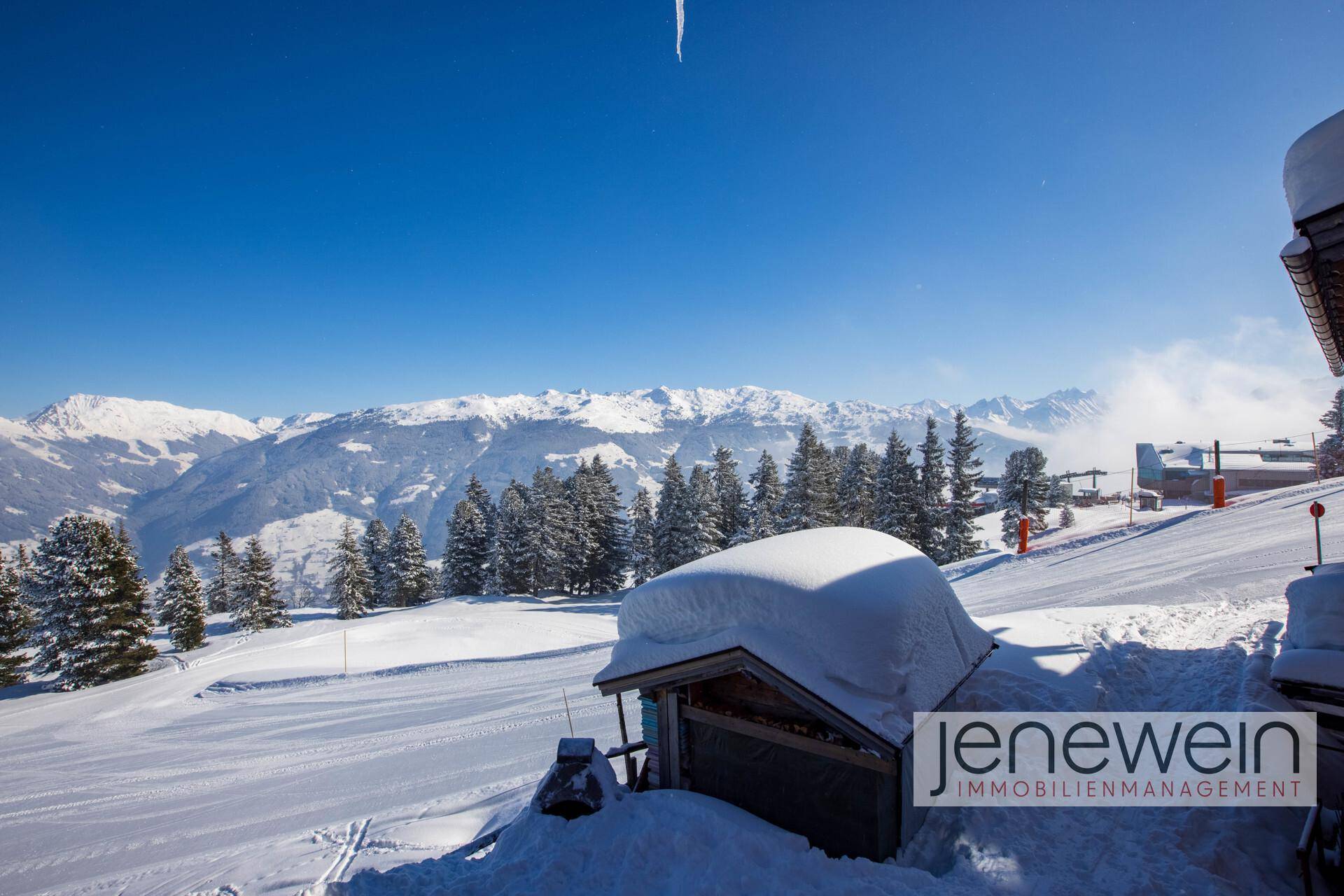 Panoramablick auf die verschneiten Berge und Skipisten unter strahlend blauem Himmel.